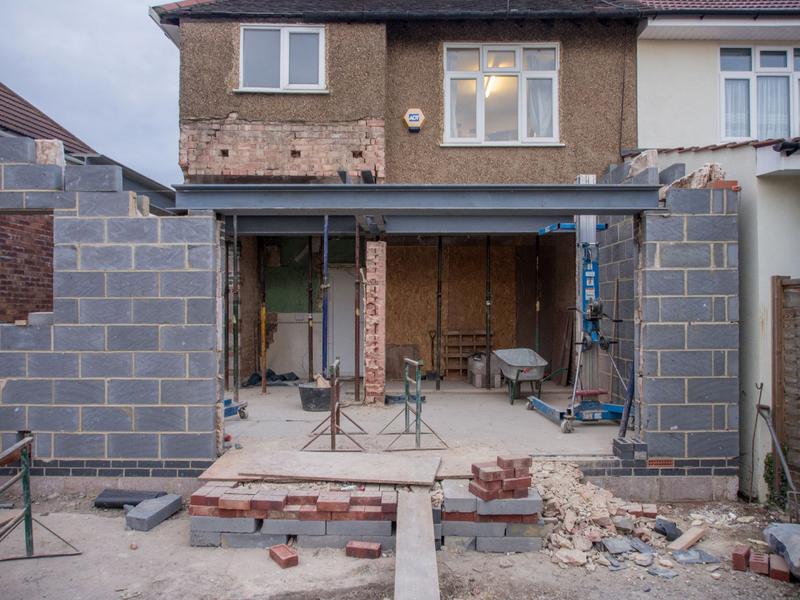 A rear extension going up on a British house: blockwork walls and a steel beam over the opening
